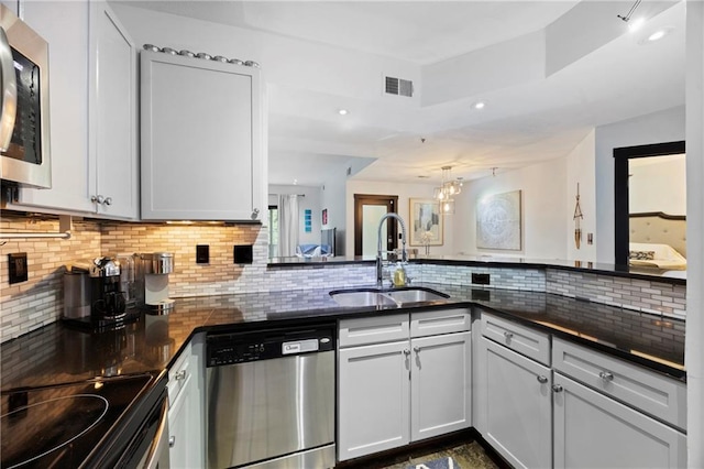 kitchen featuring stainless steel appliances, a sink, backsplash, dark countertops, and white cabinets