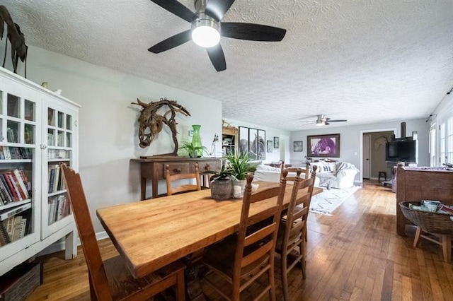 dining area with ceiling fan, wood-type flooring, and a textured ceiling