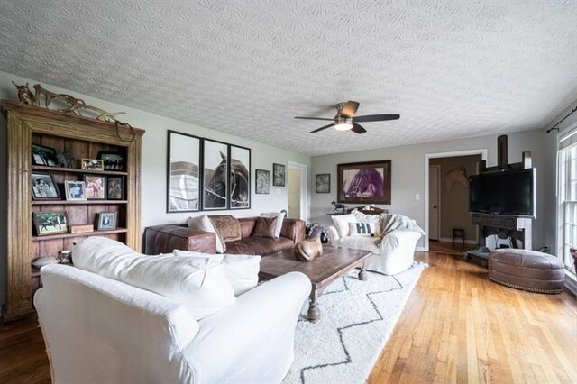 living room with ceiling fan, hardwood / wood-style floors, and a textured ceiling