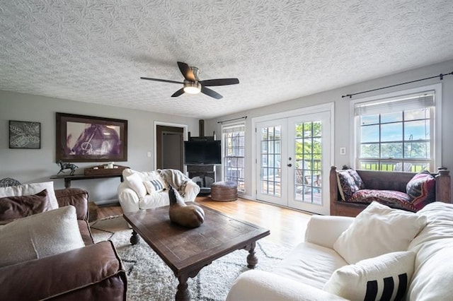 living room featuring french doors, a textured ceiling, hardwood / wood-style flooring, and ceiling fan