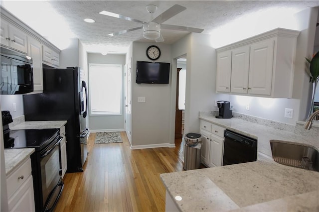 kitchen featuring white cabinetry, sink, black appliances, light stone countertops, and a textured ceiling