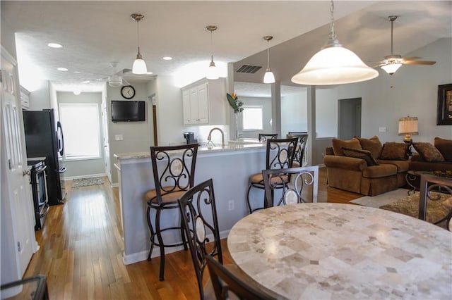 dining area with sink, ceiling fan, and light wood-type flooring