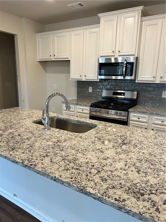 kitchen with white cabinets, appliances with stainless steel finishes, backsplash, and sink