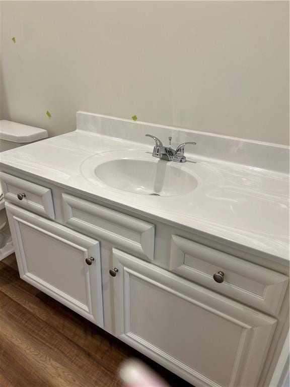 bathroom with wood-type flooring, vanity, and toilet