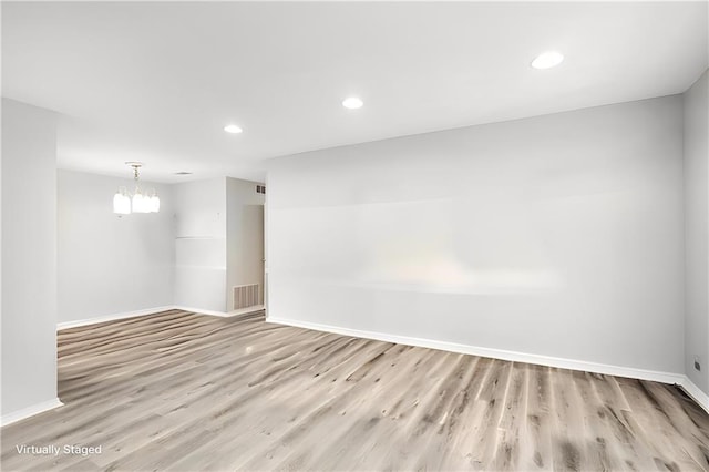 unfurnished room featuring light hardwood / wood-style flooring and an inviting chandelier