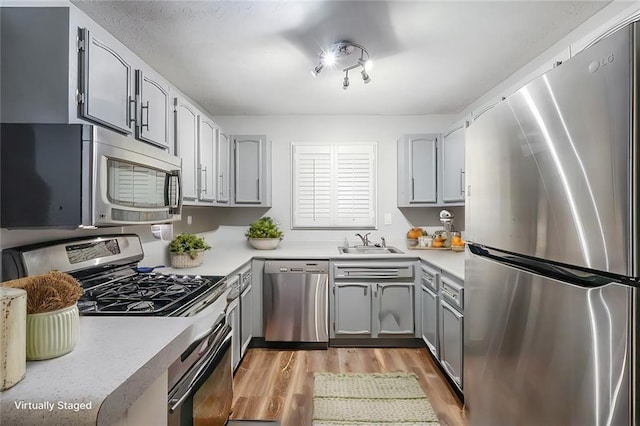 kitchen with gray cabinets, sink, light hardwood / wood-style floors, and appliances with stainless steel finishes