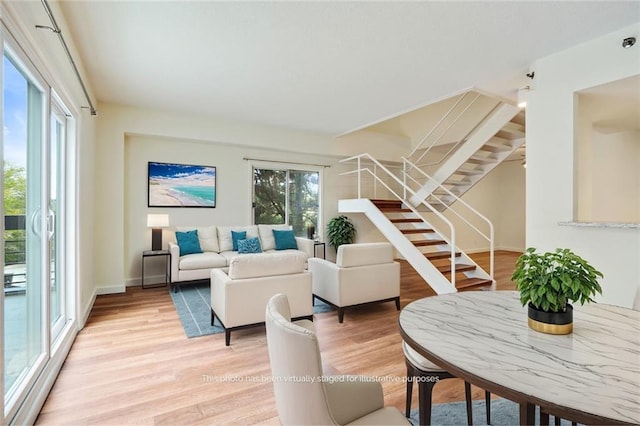 living area with stairway, plenty of natural light, light wood-style floors, and baseboards