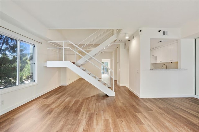 587 Virginia Ave NE Unit 315, Atlanta, GA 30306 - unfurnished living room with visible vents, baseboards, stairs, light wood-style floors, and a sink