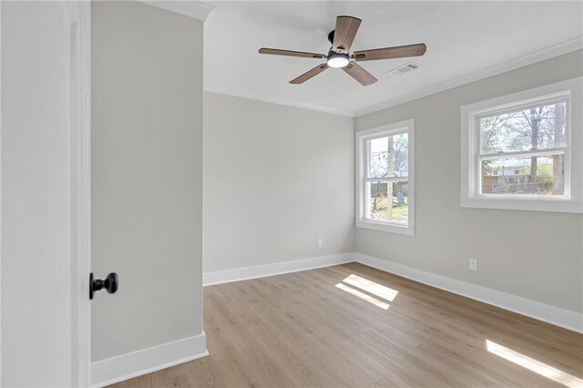empty room featuring visible vents, a ceiling fan, light wood-style floors, crown molding, and baseboards