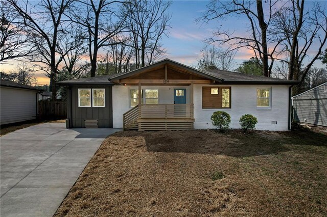 view of front of house featuring board and batten siding, concrete driveway, covered porch, and crawl space