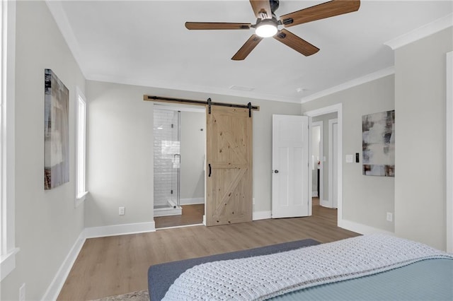 bedroom featuring a barn door, baseboards, wood finished floors, and crown molding