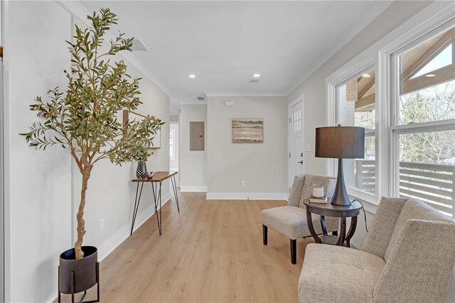 sitting room with electric panel, recessed lighting, light wood-style floors, crown molding, and baseboards