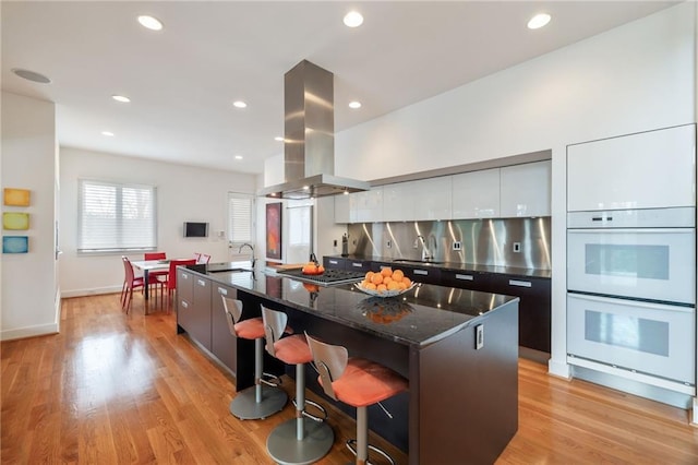 4835 Merlendale Ct, Atlanta, GA 30327 - kitchen with island exhaust hood, stainless steel stovetop, white double oven, modern cabinets, and a spacious island