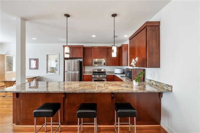 4835 Merlendale Ct, Atlanta, GA 30327 - kitchen with light stone counters, hanging light fixtures, light wood-type flooring, stainless steel appliances, and a peninsula
