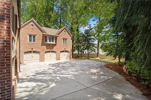 4835 Merlendale Ct, Atlanta, GA 30327 - view of side of home with brick siding, an attached garage, driveway, and fence