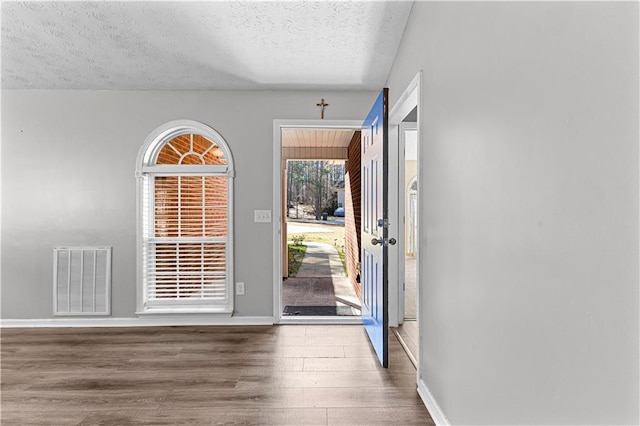 foyer with visible vents, baseboards, a textured ceiling, and wood finished floors