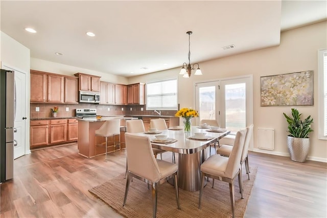 dining space with light hardwood / wood-style floors, a notable chandelier, and sink