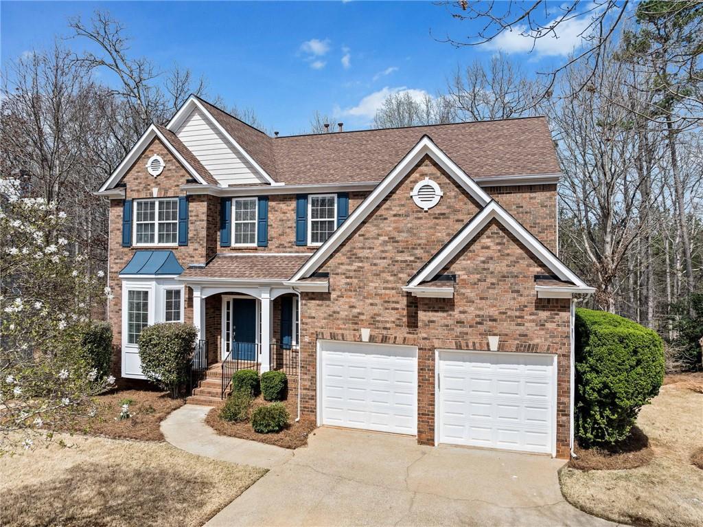 view of front facade with concrete driveway, brick siding, a garage, and a shingled roof