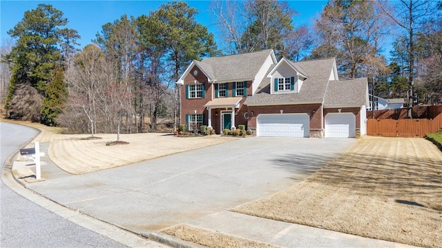 colonial inspired home featuring brick siding, concrete driveway, an attached garage, and fence