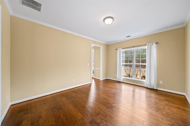 spare room featuring visible vents, baseboards, wood finished floors, and ornamental molding