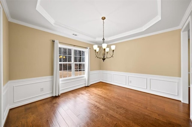 unfurnished dining area featuring a raised ceiling, a notable chandelier, wood finished floors, and visible vents