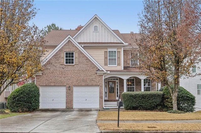 view of front of home with an attached garage, cooling unit, brick siding, driveway, and board and batten siding