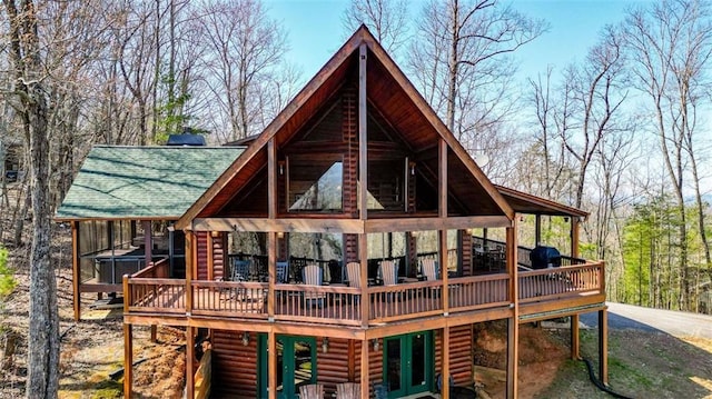 back of house featuring log veneer siding, a shingled roof, and a wooden deck