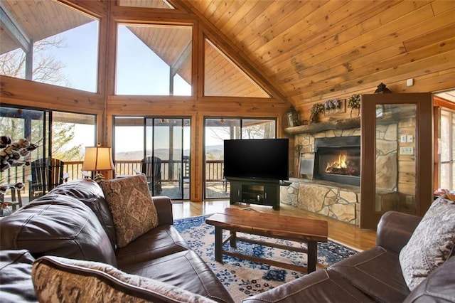 living area featuring a stone fireplace, wood finished floors, wooden ceiling, and a healthy amount of sunlight