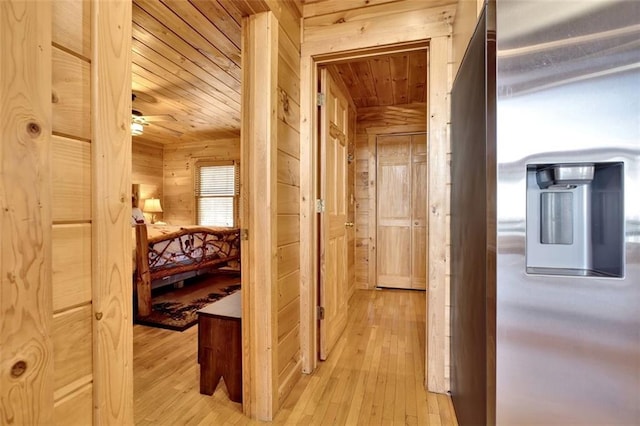 hall featuring wooden walls, wood ceiling, and light wood-style floors