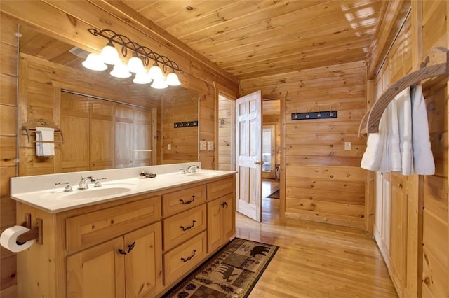 bathroom featuring double vanity, wood ceiling, wood walls, and a sink