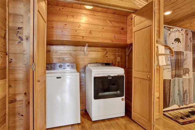 laundry area featuring washing machine and clothes dryer, laundry area, light wood-style floors, wood walls, and wooden ceiling