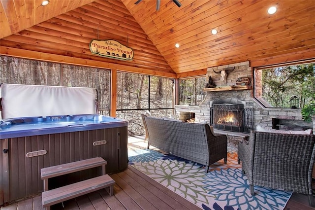 wooden deck with a gazebo, a hot tub, and an outdoor stone fireplace