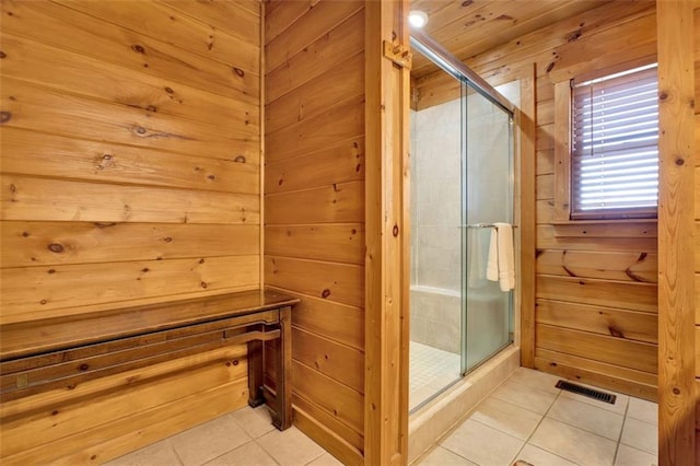 full bath with tile patterned flooring, wooden walls, a shower stall, and visible vents