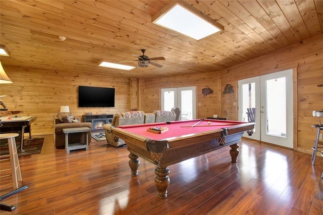 rec room with wood walls, french doors, wooden ceiling, wood finished floors, and a ceiling fan