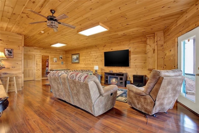 living area with ceiling fan, wood finished floors, wooden ceiling, and wood walls