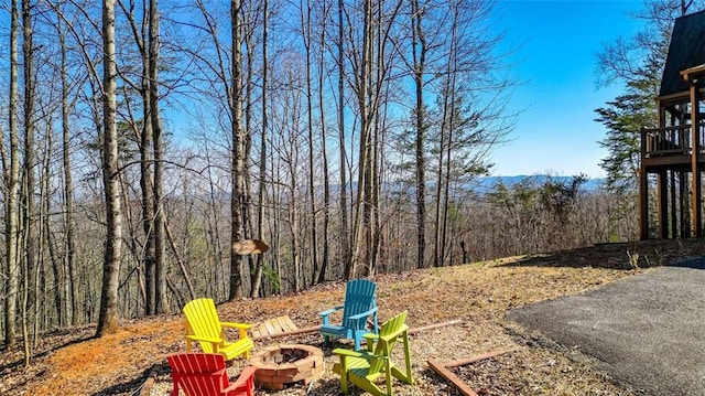 view of yard featuring a fire pit and a view of trees