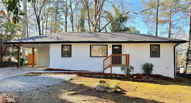 ranch-style house with brick siding, a carport, roof with shingles, crawl space, and driveway