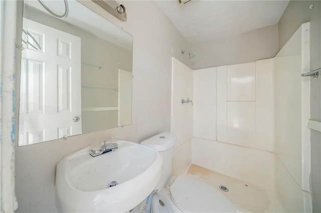 bathroom with toilet, a shower stall, and a sink