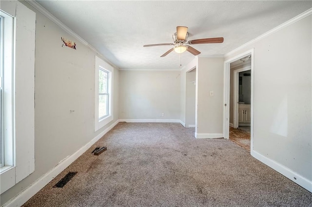 unfurnished room with visible vents, baseboards, a ceiling fan, crown molding, and carpet floors