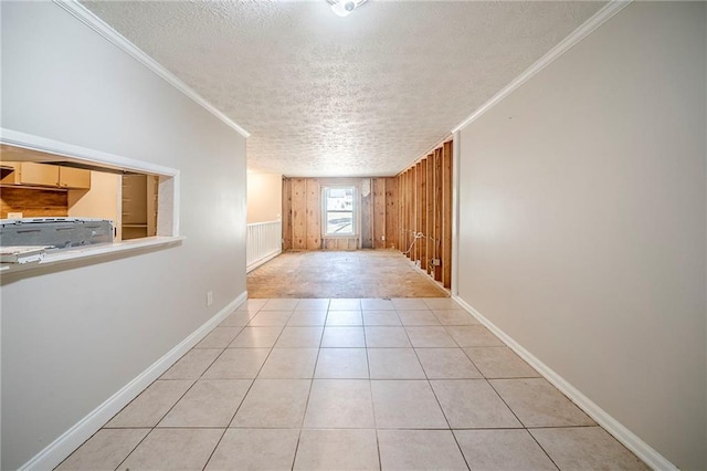 unfurnished room featuring crown molding, a textured ceiling, baseboards, and light tile patterned floors