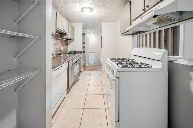 kitchen featuring light tile patterned floors, decorative backsplash, a textured ceiling, white appliances, and under cabinet range hood