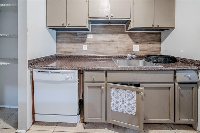 kitchen with tasteful backsplash, dishwasher, dark countertops, gray cabinetry, and a sink