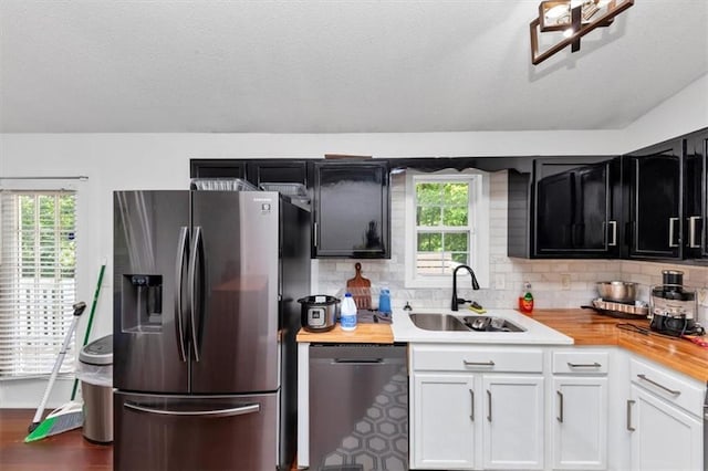 kitchen featuring stainless steel appliances, a sink, healthy amount of natural light, tasteful backsplash, and a textured ceiling