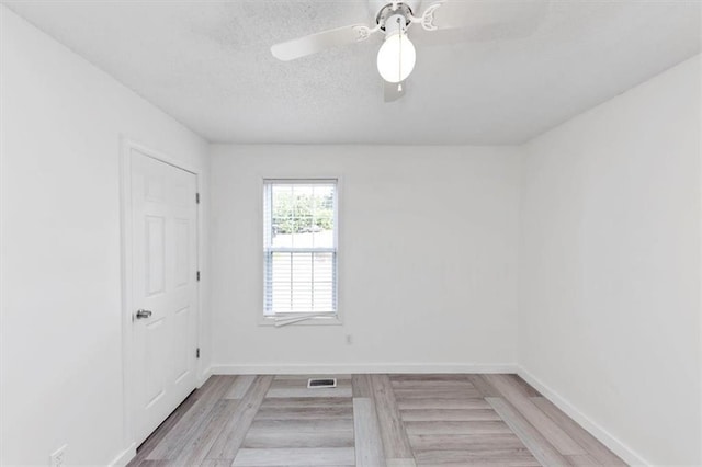 unfurnished room with light wood-style floors, a textured ceiling, baseboards, and a ceiling fan