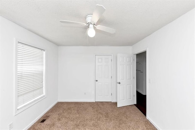 unfurnished bedroom with carpet floors, a textured ceiling, baseboards, and a ceiling fan