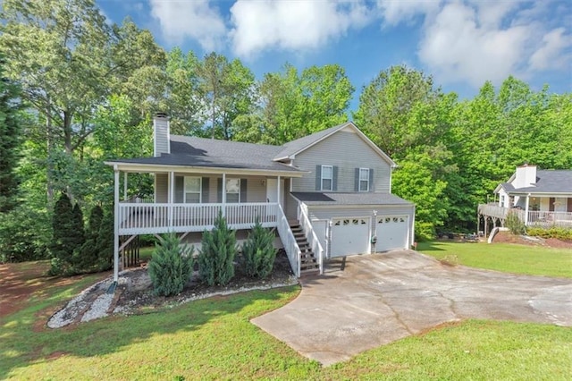 split level home with a porch, an attached garage, a chimney, driveway, and a front yard
