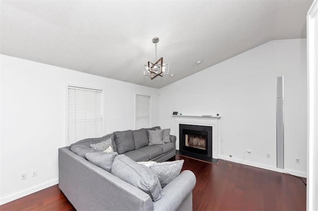 living room with lofted ceiling, a fireplace with flush hearth, dark wood-style floors, baseboards, and a chandelier