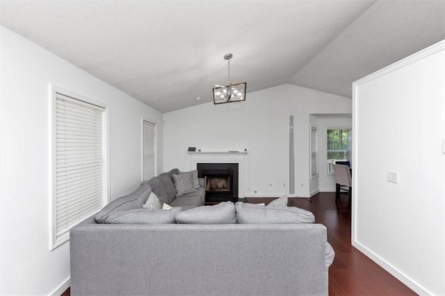 living area featuring vaulted ceiling, dark wood-style flooring, a fireplace, a chandelier, and baseboards