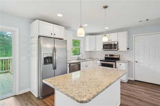 kitchen featuring appliances with stainless steel finishes, a sink, dark wood finished floors, white cabinetry, and tasteful backsplash