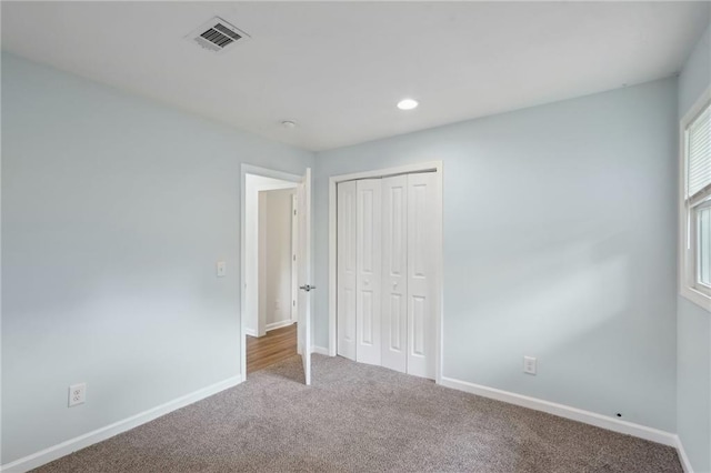 unfurnished bedroom featuring carpet flooring, baseboards, a closet, and recessed lighting